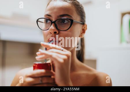 Eine junge Frau mit Gläsern, die aus einer Dose mit einem Strohhalm trinken Stockfoto
