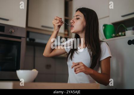 Junge Frau, die in einer modernen Küche frühstückt Stockfoto