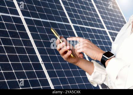 Geschäftsfrau, die ihr Smartphone auf dem Hintergrund eines großen Sonnenkollektors benutzt. Stockfoto