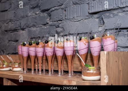 Exquisite Desserts in verschiedenen Schichten in eleganten Gläsern mit frischen Beeren. Stockfoto