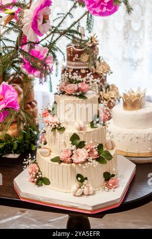 Eleganter dreistöckiger Kuchen mit Rosen und zarten Dekorationen. Stockfoto