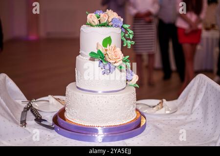 Eleganter dreistufiger Hochzeitstorte mit Blumenakzenten. Stockfoto