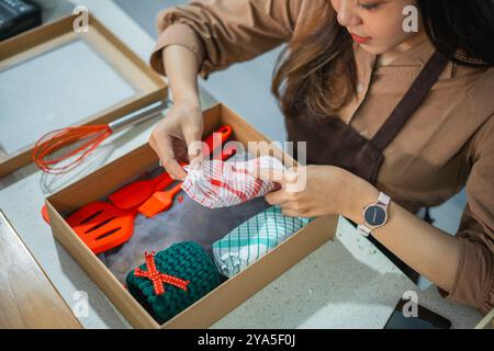 Shopgirl, das eine Geschenkbestellung mit Kochutensilien in eine Kiste legt Stockfoto