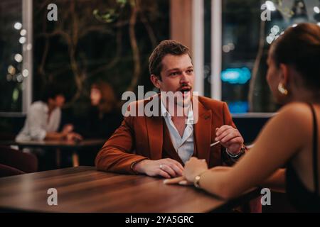 Junges Paar, das sich abends in einem stilvollen Restaurant unterhält Stockfoto