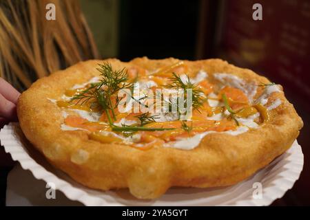 Nahaufnahme eines langos, typisch ungarische Spezialitäten, mit Sauerrahm und Fischlachs auf einem weißen Gericht auf einem braunen Tisch, frittiertem Teig bei A christ Stockfoto