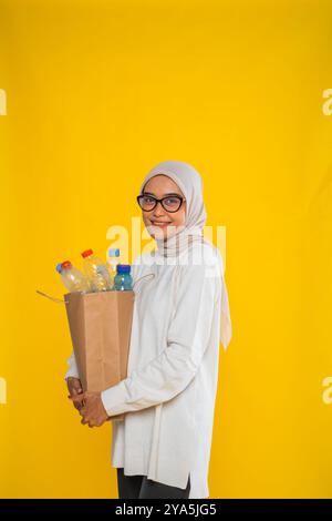 Seitenansicht einer Hijab-Frau, die Plastikflasche in Papiertüte hält Stockfoto
