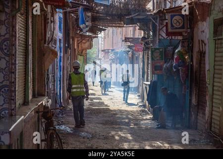 Die Morgensonne taucht diese Straße in der Medina von Marrakesch, wo die ersten Arbeiter beschäftigt sind Stockfoto