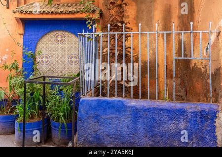 In einer Ecke der Medina von Marrakesch hebt sich diese grüne Ecke mit dunkelblauer Farbe von der rot-ockerfarbenen Umgebung ab Stockfoto