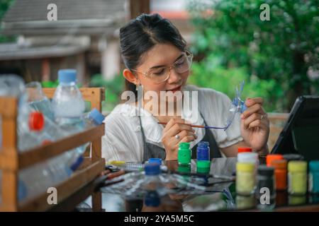Kreative asiatische Frau mit Pinsel färbende Plastikflasche Stockfoto