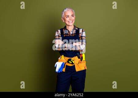 Foto der Reifen Frau professioneller Mechaniker gekreuzte Hände sehen leer Raum gekleidete blaue Arbeitskleidung insgesamt isoliert auf khakifarbenem Hintergrund Stockfoto