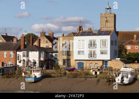 Teil des Ufers des River Colne bei Ebbe bei Wivenhoe in Essex, einschließlich des Rose and Crown Pub und St. Mary's Kirchturms. Stockfoto