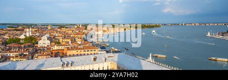 Ein weitläufiger Blick aus der Luft fängt die ikonischen Kanäle und historischen Gebäude Venedigs ein, während die Sonne untergeht, beleuchtet die Stadt mit einem warmen Leuchten und schafft eine malerische Atmosphäre. Stockfoto