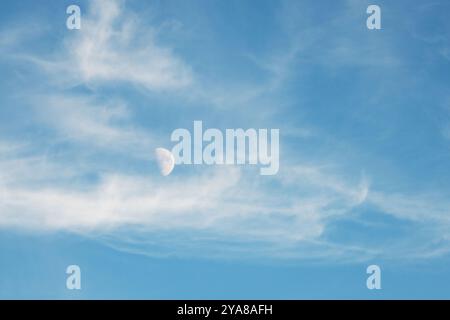 Ein Mond des ersten Viertels scheint mit den Wolken in diesem Tageslichtbild zu schweben. Stockfoto