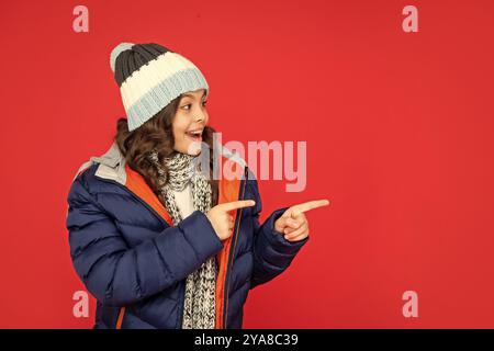 ausdruck positiver Emotion. Wintermode. Zeigefinger auf Kopierraum. Stauntes Kind Stockfoto