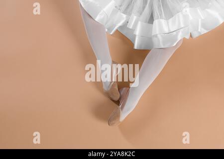 Kleine Ballerina mit spitzenschuhen auf beigefarbenem Hintergrund, Draufsicht. Leerzeichen für Text Stockfoto