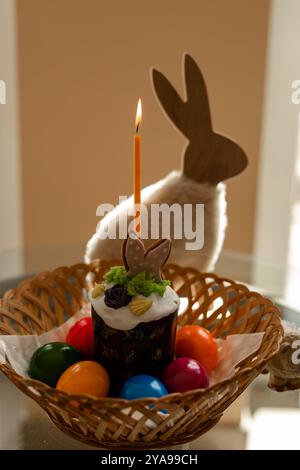 Osterkuchen mit einer zündeten Kerze. Ostereier in einem Korb auf dem Tisch. Hochwertige Fotos Stockfoto