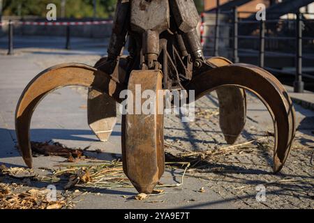 Schwerer industrieller Greifer in Aktion, sammelt an einem sonnigen Tag Schmutz und Holz. Stockfoto