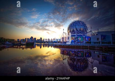 Golden-Töne des Sonnenuntergangs tauchen Science World und False Creek in Vancouver, BC, ein und werfen ein atemberaubendes Spiegelbild auf das ruhige Wasser. Stockfoto