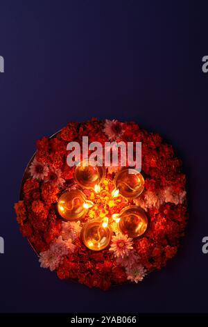 Diwali-Feier. Diya-Lampen und wunderschöne Blumen auf violettem Hintergrund, Blick von oben. Leerzeichen für Text Stockfoto