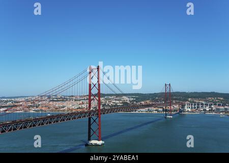 Blick auf eine rote Hängebrücke über einen Fluss, umgeben von städtischer Landschaft, Ponte 25 de Abril, Brücke 25 April, Hängebrücke über den Tejo, dou Stockfoto