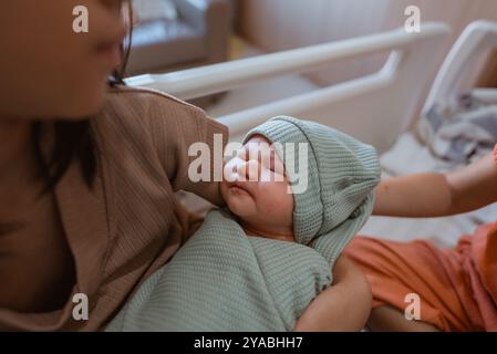 Ein neugeborenes Baby, das sanft von ihrer Mutter in einem Krankenhaus gehalten wird und Liebe ausstrahlt Stockfoto