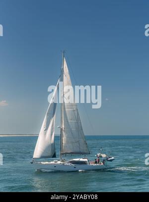 Weiße Segelyacht in ruhigem Wasser und einer klaren blauen Himmelslandschaft. Stockfoto