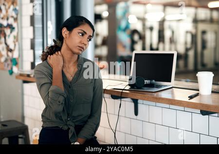 Frustrierte Frau, Nackenschmerzen und Verletzungen mit Laptop im Café für Muskelverspannungen, Ermüdung oder Belastung in kleinen Unternehmen. Junge, weibliche Person oder Freiberufler Stockfoto