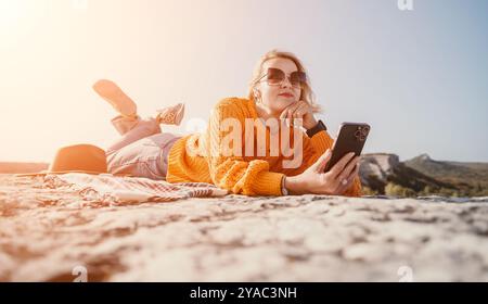 Frau, die sich auf einem Berggipfel mit Telefon entspannt Stockfoto