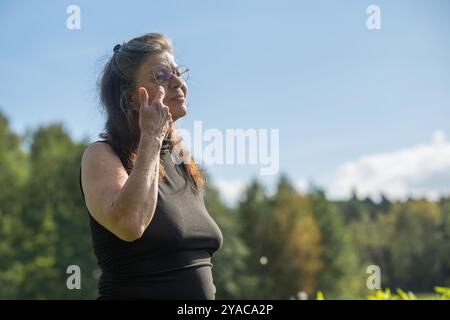 Eine ältere Frau bürstet ihr Haar aus dem Gesicht Stockfoto