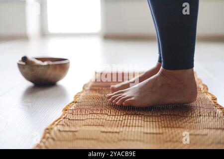 Yoga Frauenbeine stehen auf Nägeln mit singender Meditationsschale, Großansicht Stockfoto