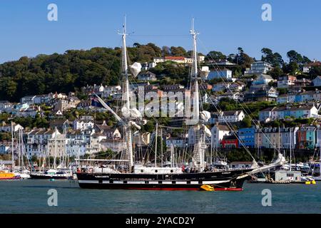 TS Royalist Training Brig liegt im River Dart mit Kingswear Marina und farbenfrohen Häusern im Hintergrund. Stockfoto