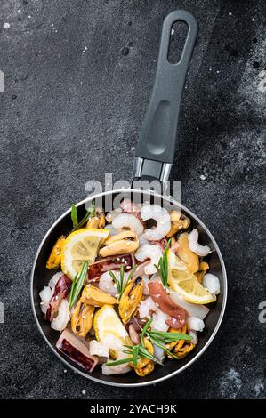 Roher Mix Meeresfrüchte-Cocktail mit Garnelen, Garnelen, Muscheln, Tintenfischen und Tintenfischen in einer Pfanne bereit zum Kochen. Schwarzer Hintergrund. Draufsicht. Stockfoto