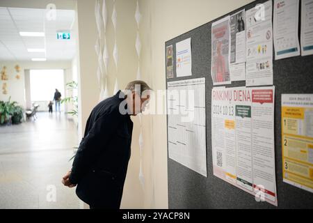 Vilnius, Litauen. Oktober 2024. Ein Mann schaut sich einen Informationsstand an einer Wahlstation an. Litauen hält die erste Runde der Parlamentswahlen zum Seimas ab. Quelle: SOPA Images Limited/Alamy Live News Stockfoto