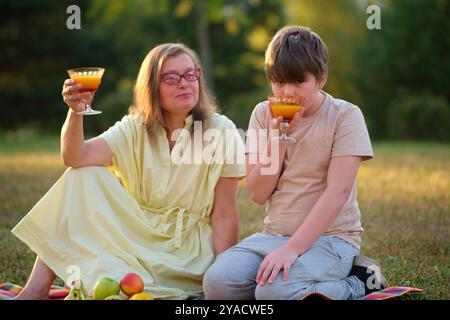 Eine glückliche Mutter und ihr Sohn genossen einen unterhaltsamen Tag in der Natur, teilten Essen und lachten. Der Teenager und seine Mutter hatten ein wunderbares Picknick Stockfoto