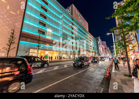 Ginza bei Nacht mit dem Wahrzeichen Matsuya Ginza und Tiffany Ladengebäude beleuchtet in blauem, grünem, diffusem Licht. Taxistände auf der Straße. Stockfoto
