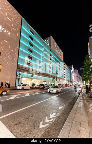 Ginza bei Nacht mit dem Wahrzeichen Matsuya Ginza und Tiffany Ladengebäude beleuchtet in blauem, grünem, diffusem Licht. Straße vor der Tür mit etwas Verkehr. Stockfoto
