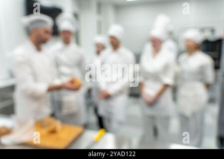 Verschwommener Hintergrund: Ein Kochlehrer oder ein Koch führt in der Produktionswerkstatt eine Meisterklasse über Brotzubereitung für seine Schüler durch. Hochwertige Fotos Stockfoto