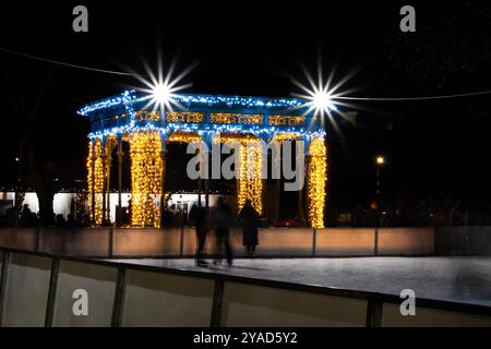 Pavillon beleuchtet mit Weihnachtslichtern neben einer Eislaufbahn bei Nacht Stockfoto