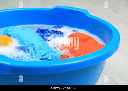 Becken mit bunten Kleidern auf dem Boden, Nahaufnahme. Handwäsche Stockfoto