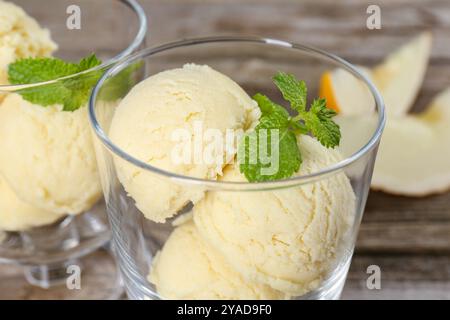 Löffel Melonensorbet und Minze in Dessertschalen aus Glas auf dem Tisch, Nahaufnahme Stockfoto