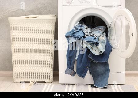 Waschmaschine mit schmutzigen Jeans und anderen Denim-Kleidern im Innenbereich Stockfoto