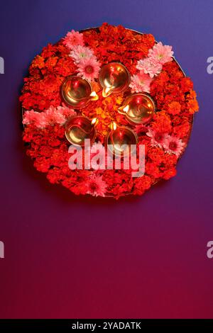 Diwali-Feier. Diya-Lampen und wunderschöne Blumen auf farbigem Hintergrund, Blick von oben. Leerzeichen für Text Stockfoto