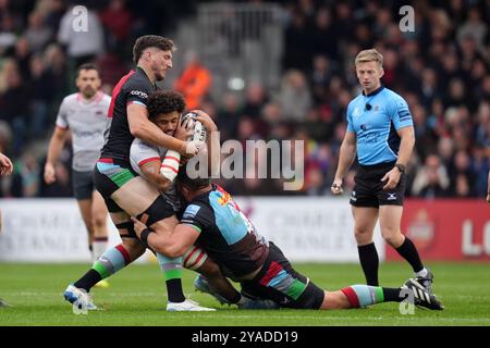 Saracens’ Andy Onyeama-Christie wird von Harlequins’ Dino Lamb (links) und Irne Herbst während des Gallagher Premiership Matches im Twickenham Stoop Stadium in London angegriffen. Bilddatum: Sonntag, 13. Oktober 2024. Stockfoto