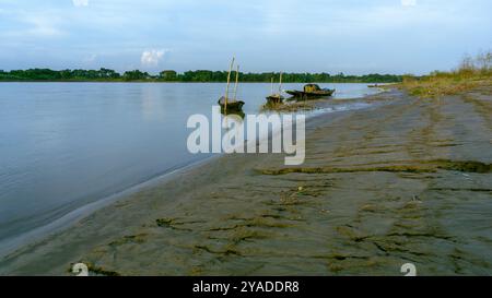 Fluss Gorai-Madhumati. Am Flussufer von Bangladesch. Am Abend legen Fischerboote am Flussufer fest. Der Fluss fließt unter dem Abendhimmel. Stockfoto