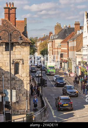 Blick über die Straßenkreuzung von Bootham in York. Die Fahrzeuge warten an der Ampel neben einem alten Torategebäude mit einer zerfallenden Mauer. Stockfoto