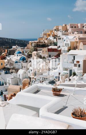 SANTORINI, GRIECHENLAND - 30. September 2024: Traditionelles griechisches Dorf Oia von Santorini, mit blauen Kuppeln von Kirchen und dörflichen Dächern, Griechenland Stockfoto