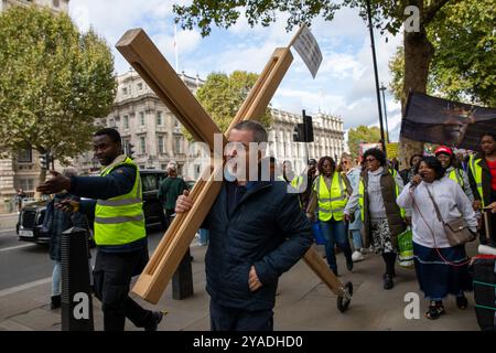 Ein Schüler Christi trägt während des marsches ein hölzernes Kreuz durch Central London. Hunderte von Christen nahmen am Marsch für Jesus Teil. Die Jünger Christi hielten dann eine Kundgebung am Trafalgar Square ab, wo sie Reden, Livemusik und Gebete hörten. Stockfoto