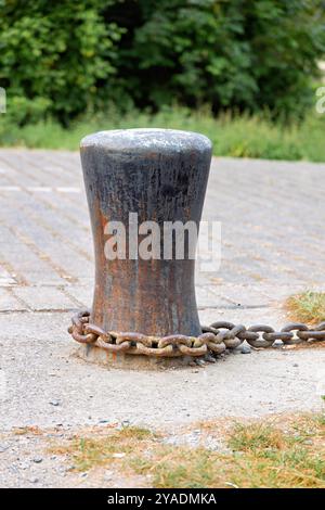 Alter rostiger Poller für Ketten und Anker, mit rostiger Kette befestigt Stockfoto