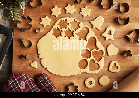 Ausgerollter Teig mit ausgeschnittenen Formen auf einem Holzbrett - Zubereitung von selbstgemachten Linzer-Keksen, Blick von oben Stockfoto