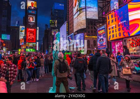 Am Times Square versammeln sich die Menschenmassen bei Nacht mit beleuchteten Reklametafeln und Straßenkünstlern in New York City. USA. Stockfoto